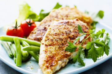 Petto di pollo grigliato con fagiolini, pomodorini e prezzemolo, un piatto sano della filiera avicola italiana.