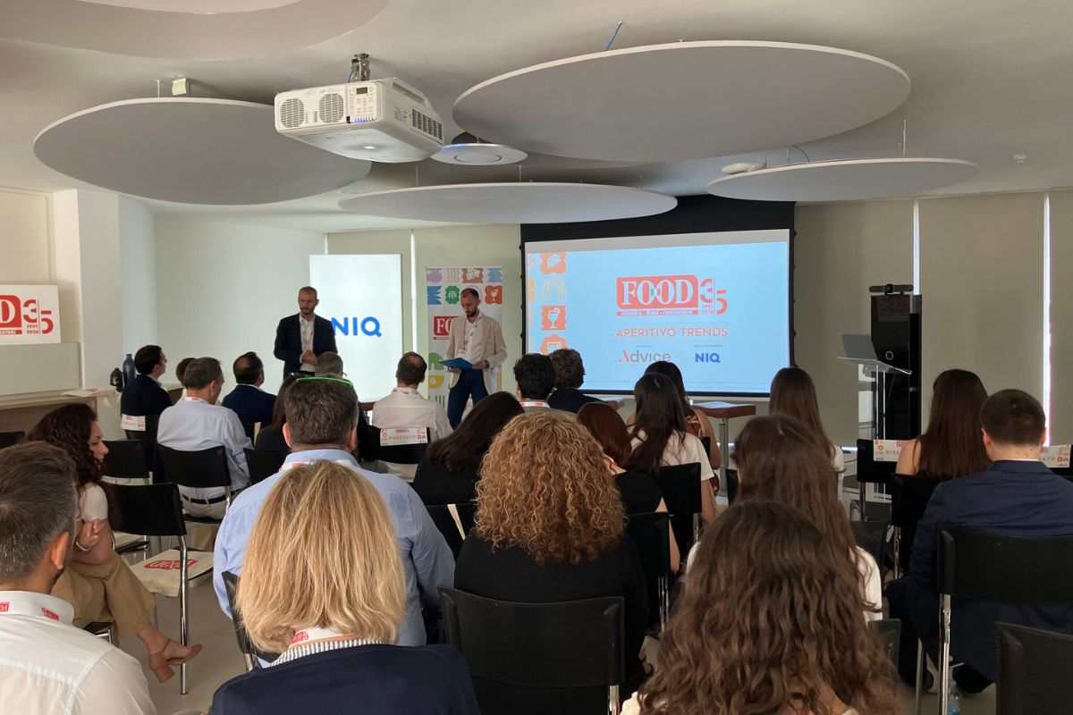 Conferenza professionale sui trend dell'aperitivo e strategie di mixology con relatori e pubblico in sala.