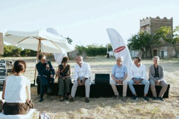 Conferenza all'aperto Granoro Dedicato: relatori seduti su un palco in campagna per promuovere la filiera del grano.