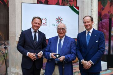 Tre uomini in giacca e cravatta celebrano i 20 anni di Italia del Gusto, consorzio dell'agroalimentare italiano.