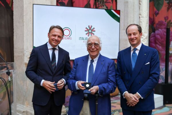 Tre uomini in giacca e cravatta celebrano i 20 anni di Italia del Gusto, consorzio dell'agroalimentare italiano.