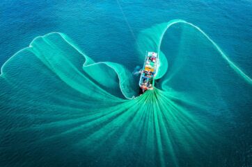 Veduta aerea di un peschereccio che utilizza reti da pesca in mare aperto per l'industria ittica sostenibile.