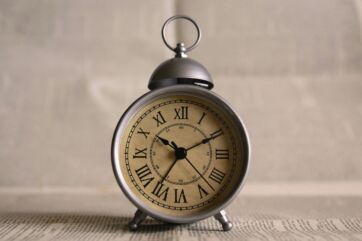 Sveglia vintage su sfondo di giornale per rappresentare l'algoritmo e la gestione del tempo in modo efficace.