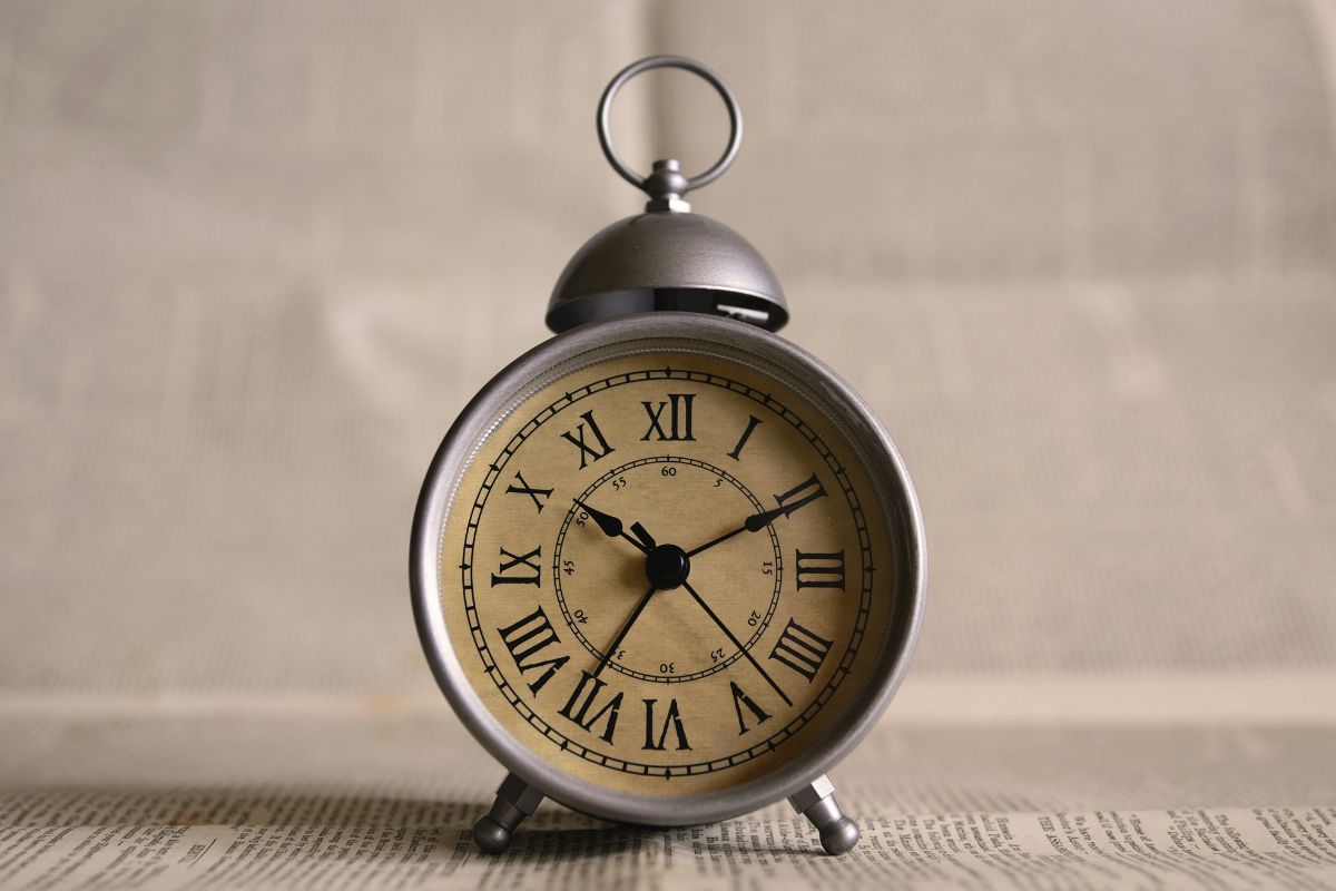 Sveglia vintage su sfondo di giornale per rappresentare l'algoritmo e la gestione del tempo in modo efficace.
