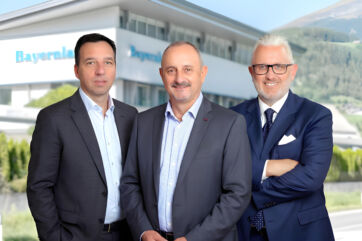 Tre manager in giacca e cravatta davanti alla sede di Bayernland Italia per il cambio al vertice aziendale.