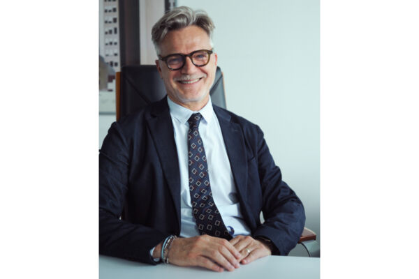 Alessandro Camattari, professionista sorridente in giacca e cravatta seduto alla scrivania in ufficio. - Dit - Distribuzione italiana-Sigma - Sisa-centrale d'acquisto