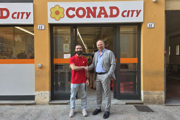 Inaugurazione del nuovo punto vendita Conad City a Modena: due uomini si stringono la mano davanti all'ingresso del negozio.