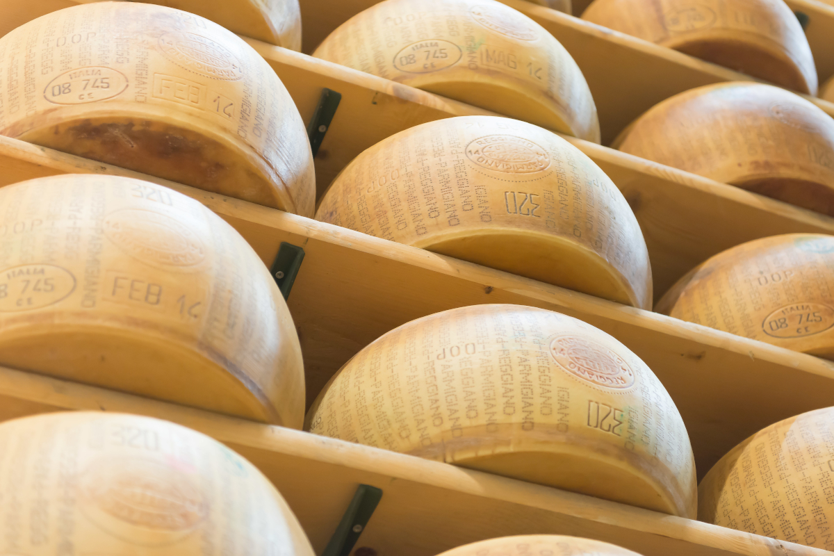 Forme di Parmigiano Reggiano DOP stagionate sugli scaffali di legno in magazzino DalterFood Group.