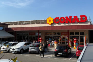 Esterno del supermercato Conad a Castelnovo ne' Monti con insegna rinnovata e clienti all'ingresso.
