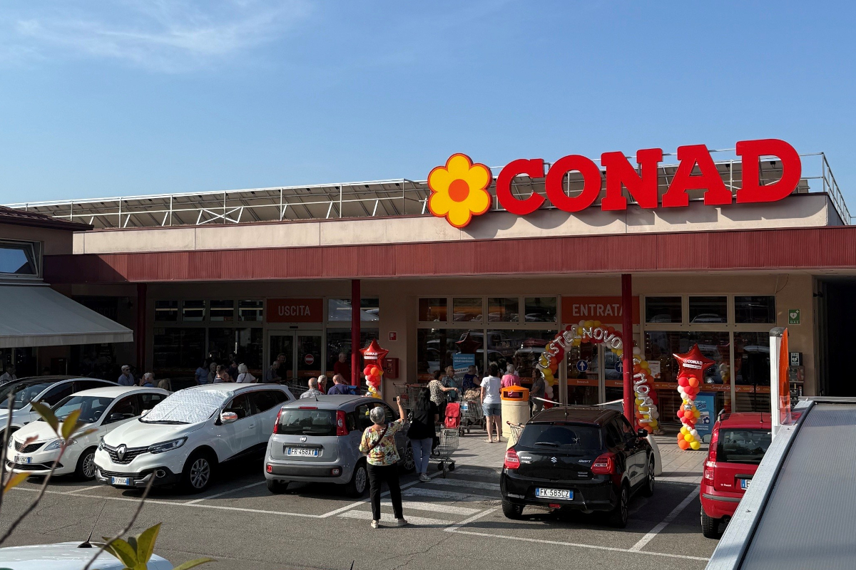 Esterno del supermercato Conad a Castelnovo ne' Monti con insegna rinnovata e clienti all'ingresso.