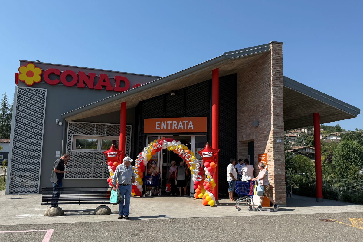 Inaugurazione Conad City a Villa Minozzo con ingresso decorato da palloncini e clienti che entrano nel supermercato.