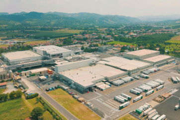 Veduta aerea del polo produttivo Gruppo Amadori, con stabilimenti industriali e logistica di camion in movimento.