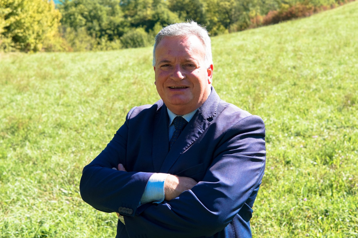 Pietro Bellini, Presidente del Consorzio Prosciutto di Norcia IGP, in giacca e cravatta in un prato verde.