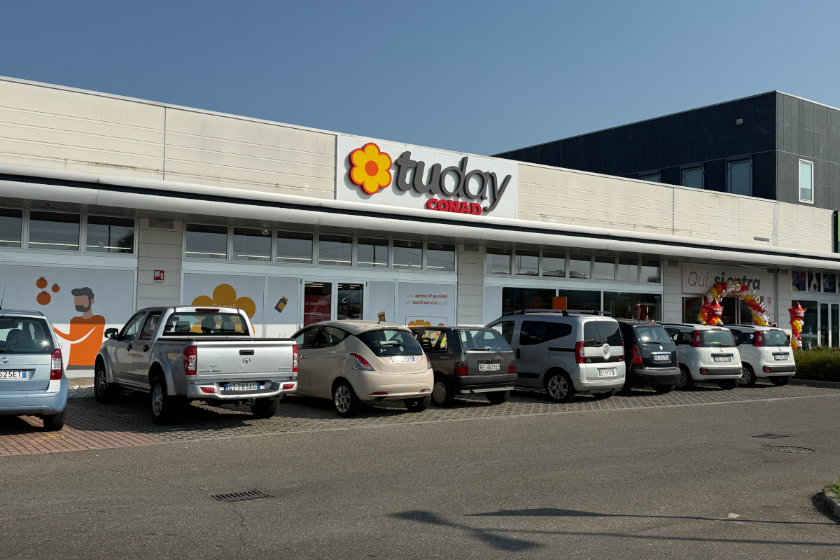 Facciata esterna del nuovo supermercato Tuday Conad a Montecchio Emilia con parcheggio antistante e auto in sosta.
