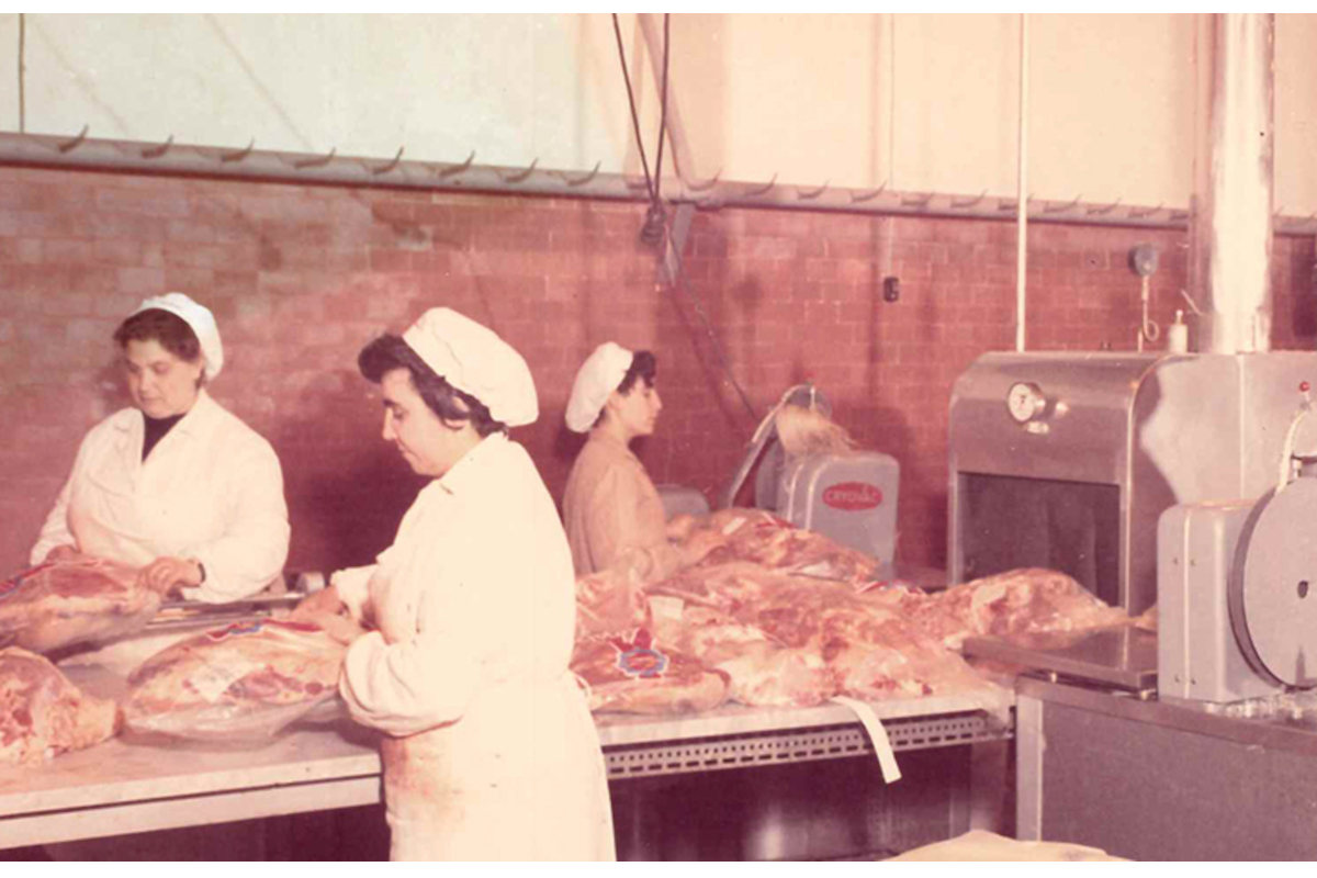 Operai al lavoro su una linea di confezionamento sottovuoto Cryovac per carne, in una storica industria alimentare. - Cryovac