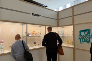 Visitatori osservano prodotti lattiero-caseari innovativi esposti nello stand Dairy al PLMA New Product Expo.