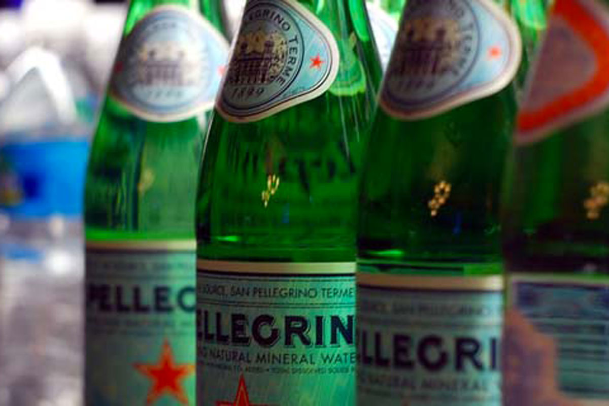 Bottiglie di acqua minerale San Pellegrino in vetro verde con etichette distintive del marchio.