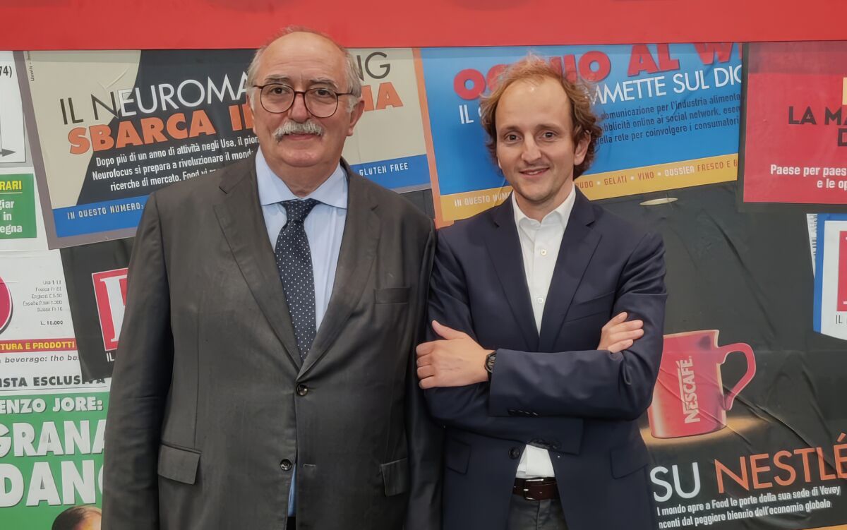 Paolo e Davide posano davanti a uno sfondo con titoli di giornale