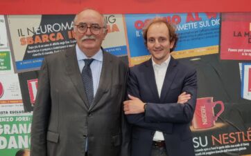 Paolo e Davide posano davanti a uno sfondo con titoli di giornale