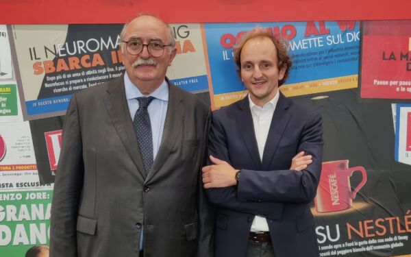 Paolo e Davide posano davanti a uno sfondo con titoli di giornale