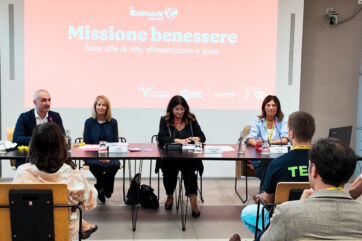 Conferenza stampa Italmark e Fondazione Veronesi per Missione Benessere: relatori sul palco e schermo proiettato.
