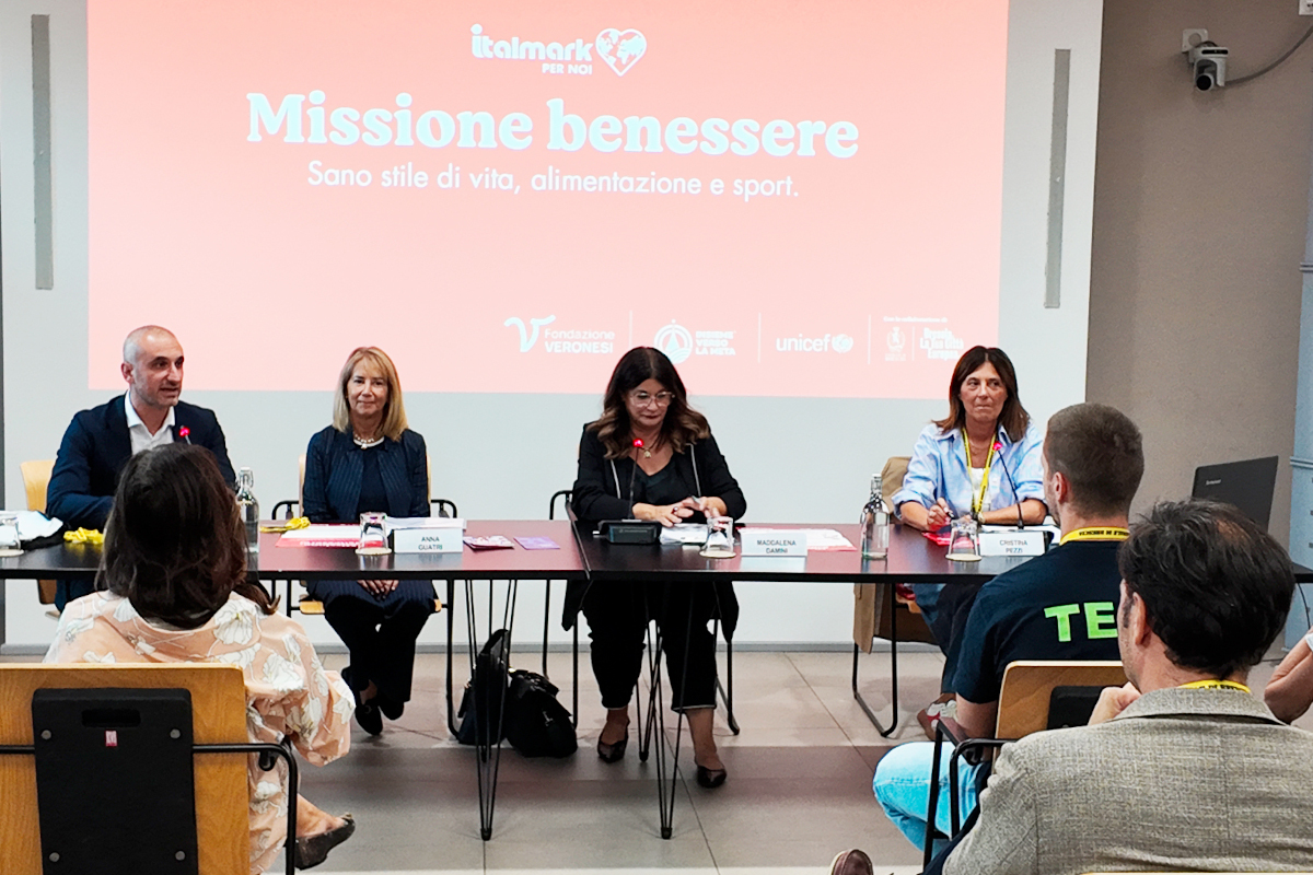 Conferenza stampa Italmark e Fondazione Veronesi per Missione Benessere: relatori sul palco e schermo proiettato.