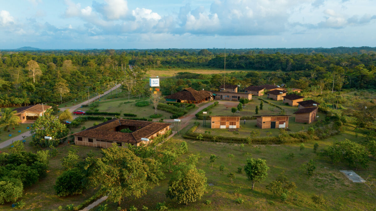 Veduta aerea di una piantagione di cacao con edifici rurali, alberi e foresta tropicale per il nuovo cioccolato fondente Ritter Sport.