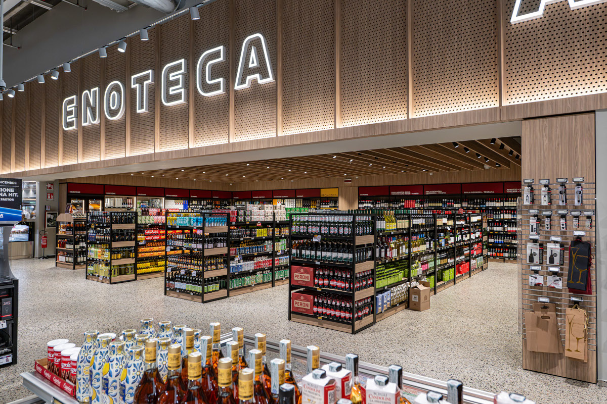 Reparto Enoteca del supermercato Esselunga a Treviglio con scaffali di vini, insegna luminosa e bottiglie esposte.