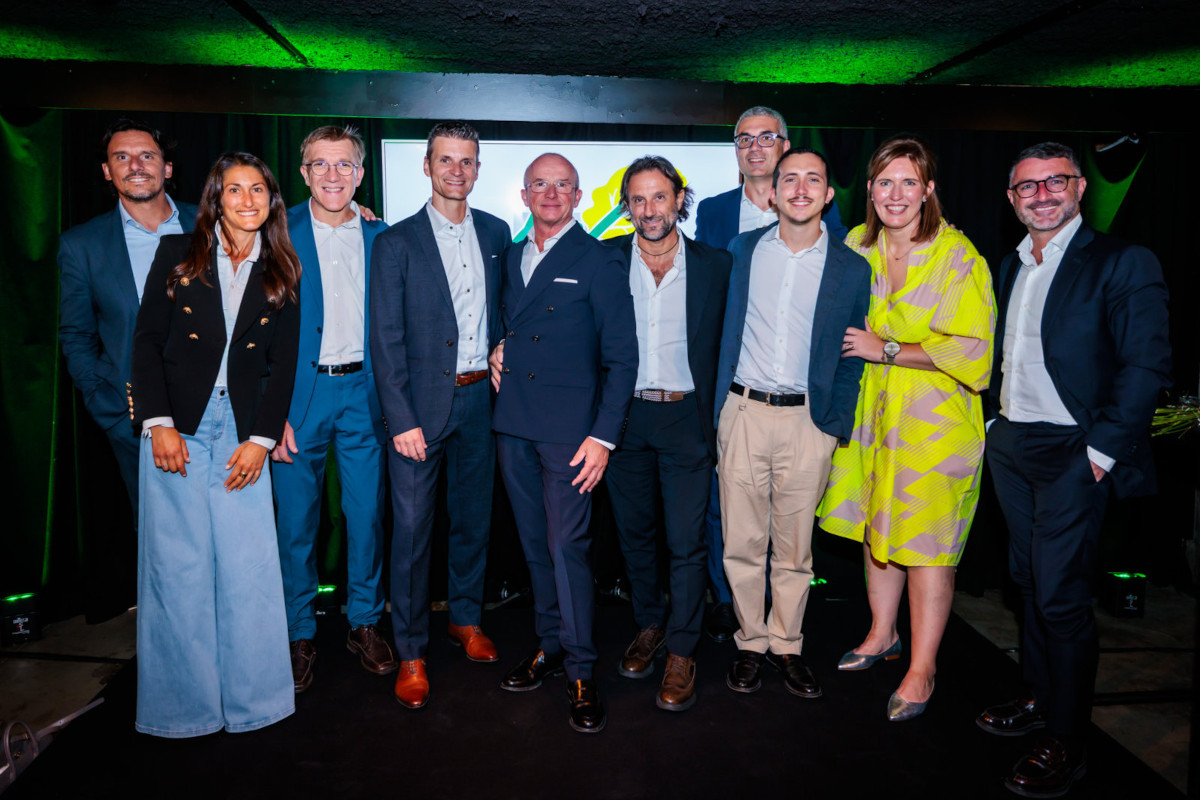 Il team di La Linea Verde Benelux posa sorridente durante l'evento BCS: gruppo di professionisti in abbigliamento elegante sul palco.
