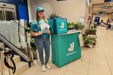 Hostess Deliveroo con shopper e stand promozionale nel supermercato Sole365 per la spesa a domicilio.