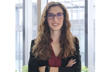 Marta Riboldi, Junior Category Manager di Crai, ritratta in ufficio con blazer nero e camicia bordeaux.