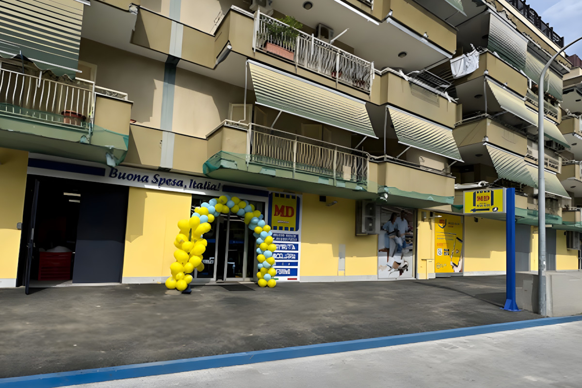 Facciata del punto vendita MD a Mugnano di Napoli con arco di palloncini gialli e blu per la riapertura del supermercato.