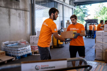 Volontari Banco Alimentare in magazzino distribuiscono scatole di cibo per contrastare la povertà