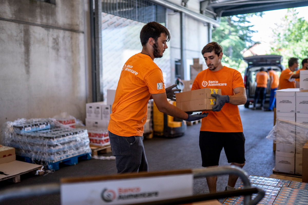 Volontari Banco Alimentare in magazzino distribuiscono scatole di cibo per contrastare la povertà