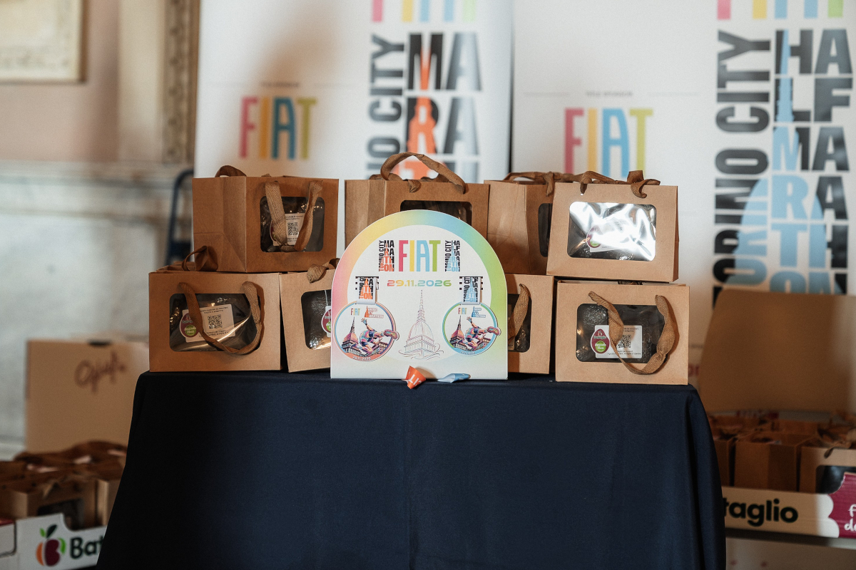 Esposizione di bag e gadget Befana sponsor alla Fiat Torino City Marathon 2026 su tavolo.
