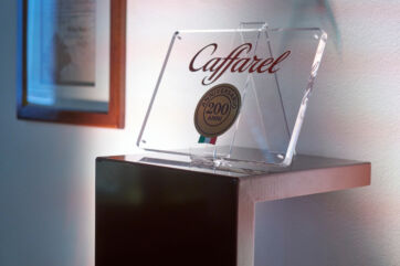 Targa in plexiglass Caffarel 200 anni con logo e stemma tricolore su mensola, celebrazione anniversario cioccolato
