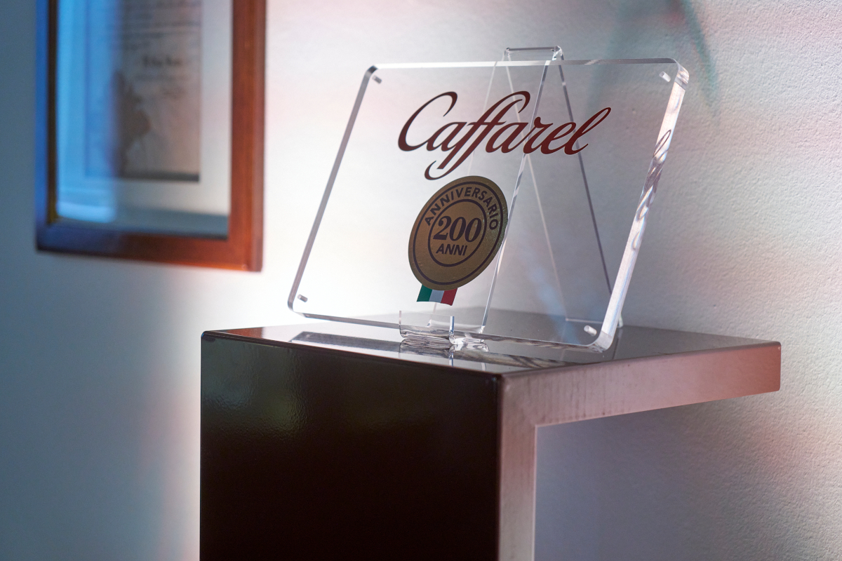 Targa in plexiglass Caffarel 200 anni con logo e stemma tricolore su mensola, celebrazione anniversario cioccolato