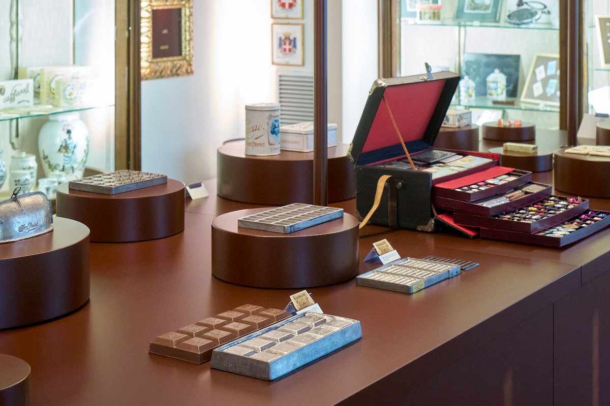 Esposizione di cioccolatini e tavolette Caffarel su bancone elegante, con scatole regalo e confezioni di praline assortite.