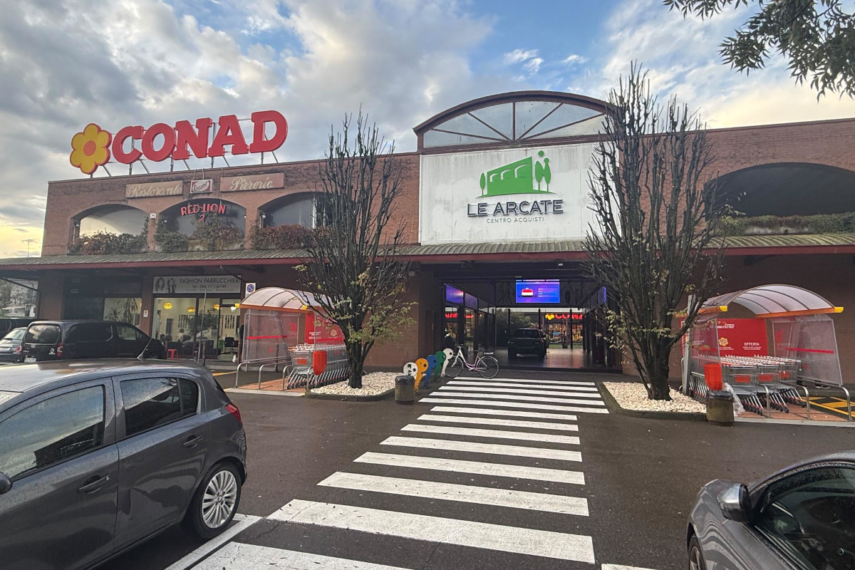 Ingresso supermercato Conad Centro Nord a Montecchio Emilia, insegna Le Arcate e parcheggio con auto.