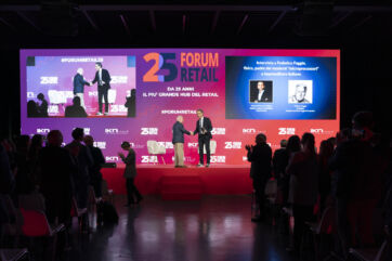 Forum Retail 2025: relatori sul palco e maxischermo con logo 25 anni, pubblico in sala all'evento.