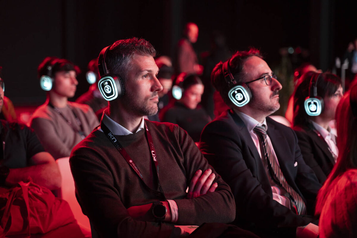 Pubblico con cuffie luminose assiste al Forum Retail 2026, focus sull'intelligenza artificiale nel settore retail.