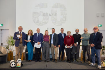 Gruppo di relatori all'evento Mulino Bianco e WWF Italia per la biodiversità, con peluche panda sul palco e scritta Grazie sullo sfondo.
