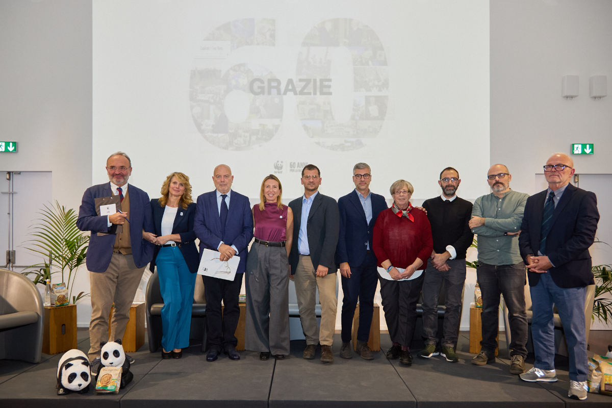 Gruppo di relatori all'evento Mulino Bianco e WWF Italia per la biodiversità, con peluche panda sul palco e scritta Grazie sullo sfondo.