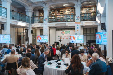 Evento sulla competitività con relatori e pubblico nella sala conferenze storica