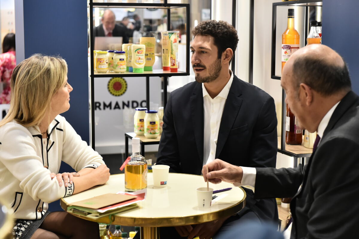 Professionisti discutono trend food a un tavolo espositivo al SIAL Paris 2026 con bevande e stand
