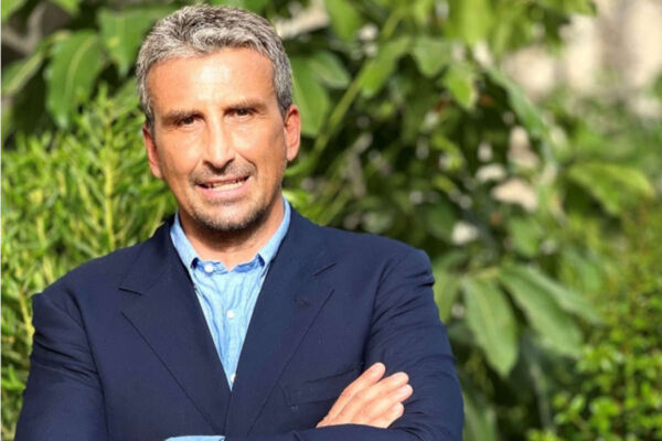 Luca Busi, AD di Sibeg Coca-Cola, in giacca blu a braccia conserte su sfondo verde: sugar tax e proteste.