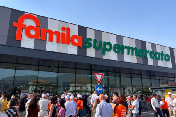 Ingresso affollato del supermercato Famila, insegna per Unicomm e progetto Spesa Difesa-Selex