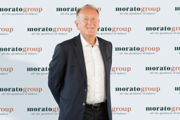 Ritratto di un uomo d'affari sorridente del Morato Group, leader nel settore bakery, su sfondo con logo aziendale.