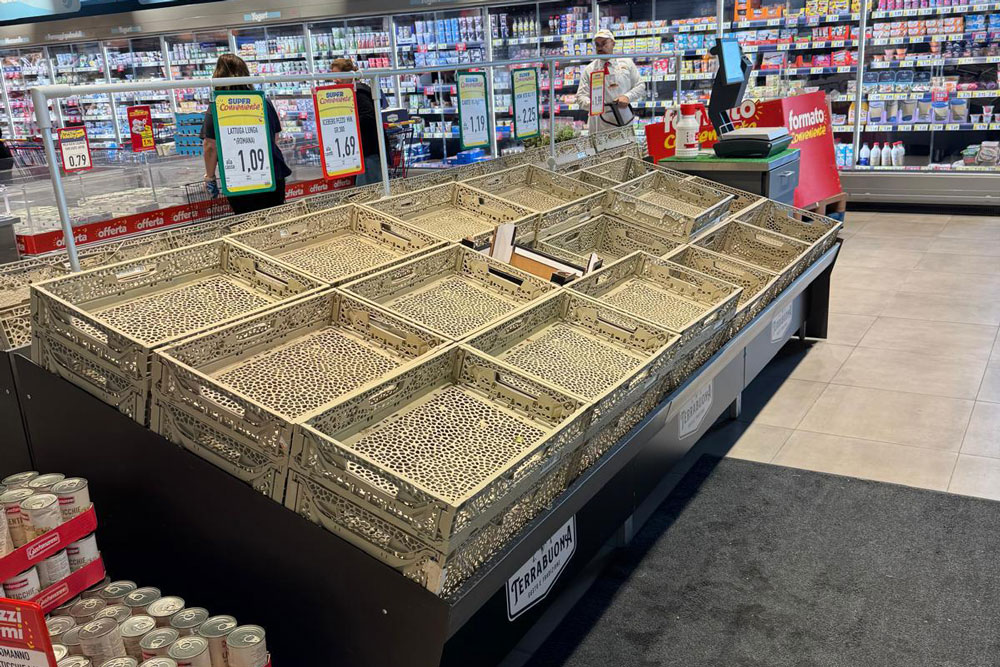 Scaffali vuoti nel reparto ortofrutta del supermercato: cestoni in legno senza merce per il blocco dei trasporti