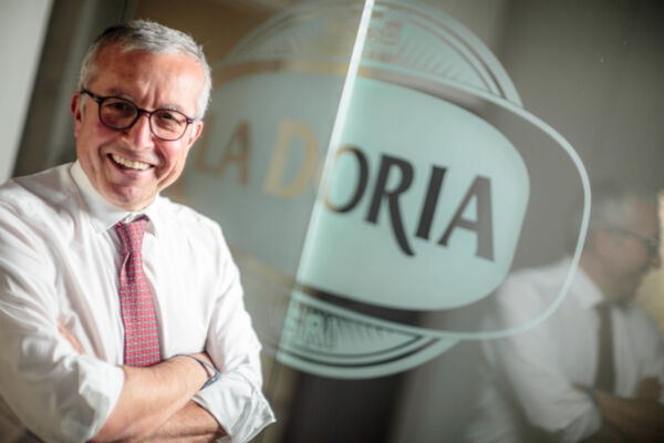 Antonio Ferraioli, CEO La Doria, smiles confidently. Man in shirt and tie, arms crossed, near La Doria logo. Business portrait.